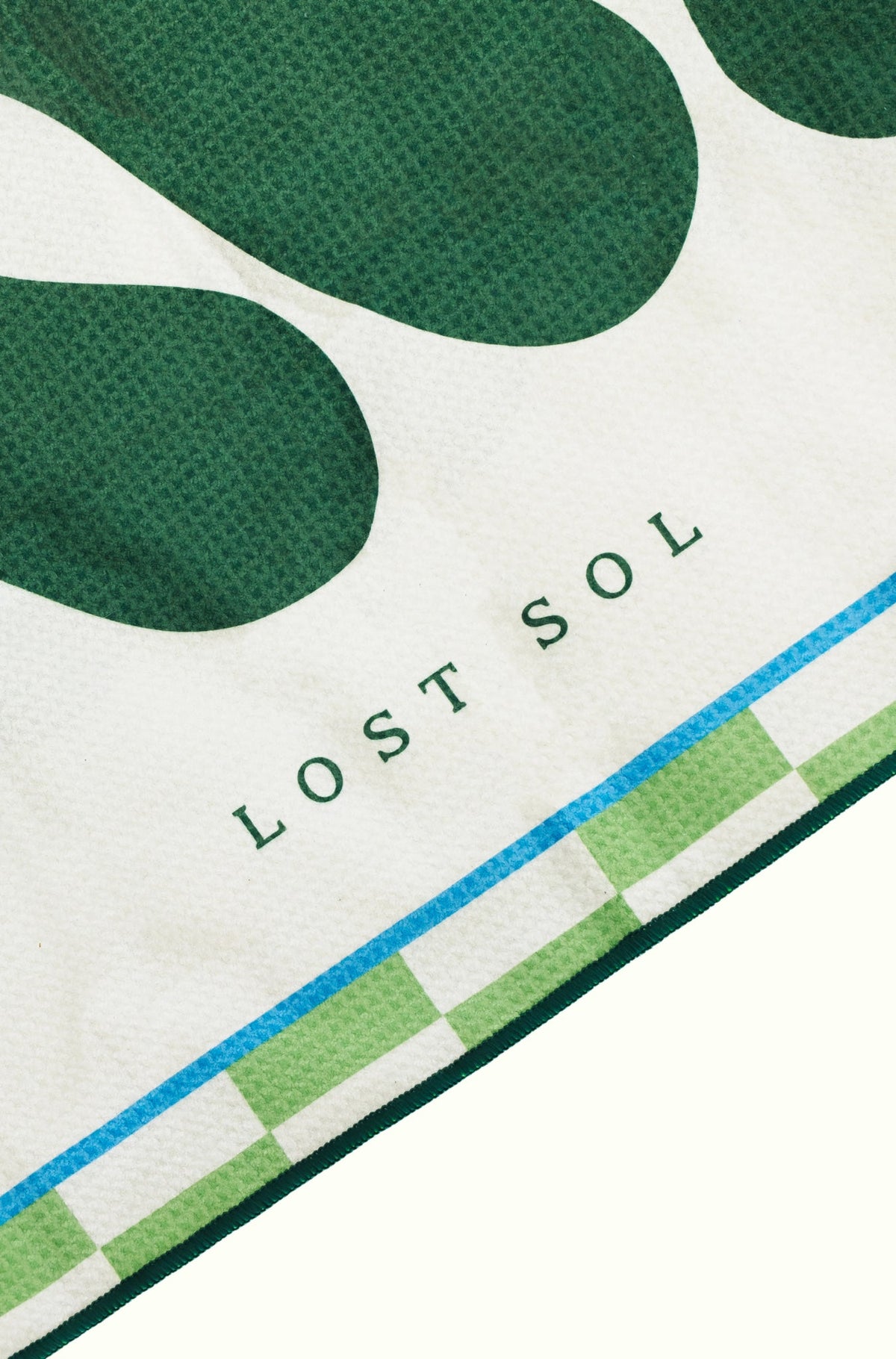 Byron Bay Bold quick-dry microfibre towel in deep green, folded product shot on a yellow background