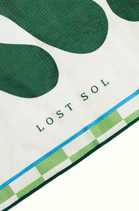 Byron Bay Bold quick-dry microfibre towel in deep green, folded product shot on a yellow background