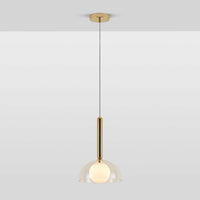 A pendant light that features a brass oval metal body attached to a clear glass dome shade which encases an opal glass shade. The light is switched on.