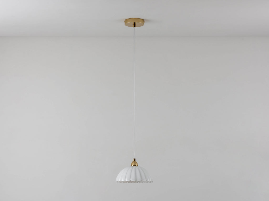 A flower-shaped milky-coloured glass mould shade is attached to an adjustable ceiling pendant cable. Light is off.