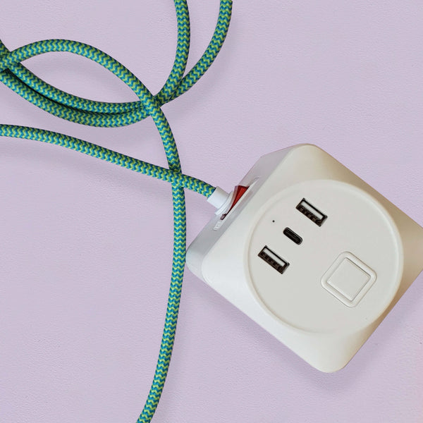 A cuboid extension lead with three plug sockets and three USB sockets, including one USB-C port with green herringbone fabric. Set against a pale lilac background.