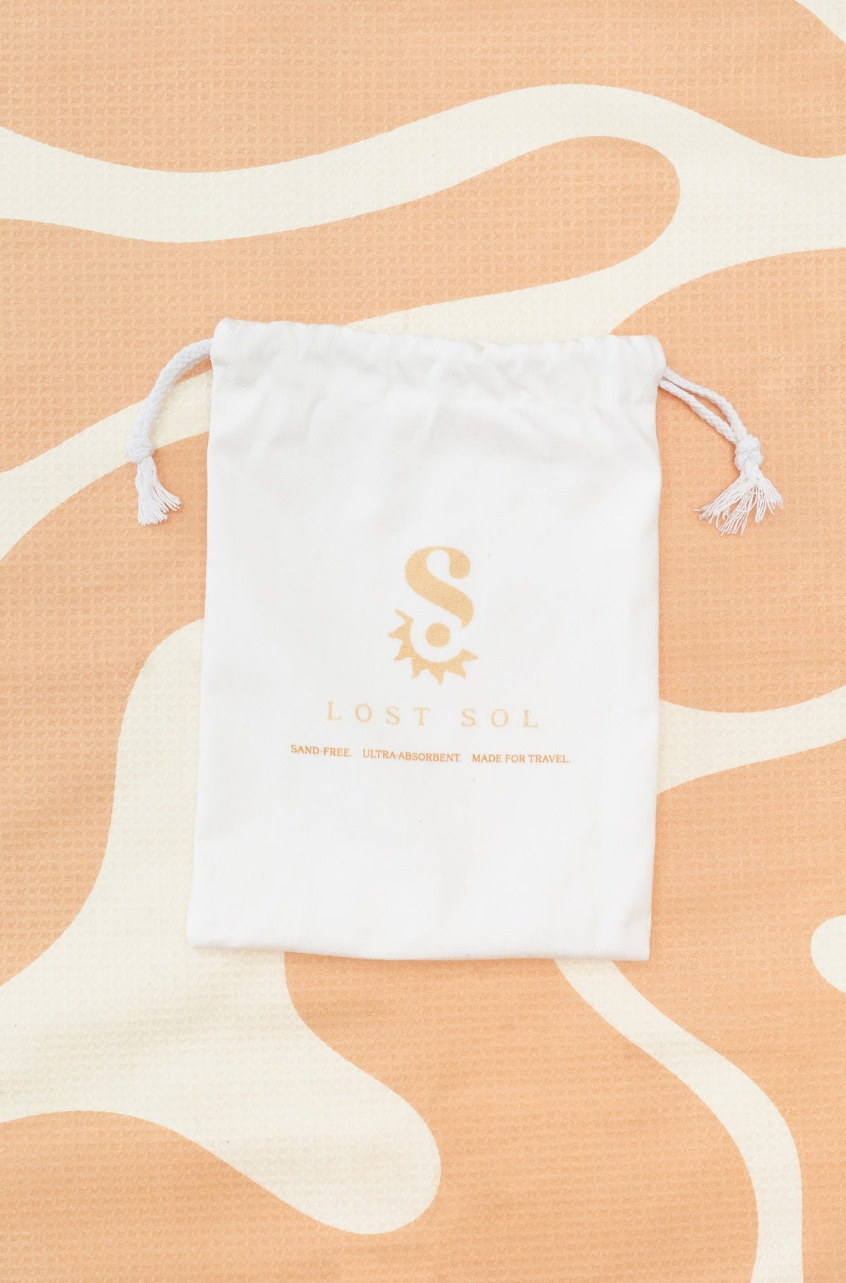 Compact packable Lost Sol Mallorca Pastel microfibre towel in soft peach, lifestyle photo