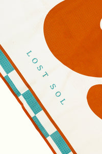 Mallorca Bold quick-dry microfibre towel in burnt orange, folded product shot on a yellow background