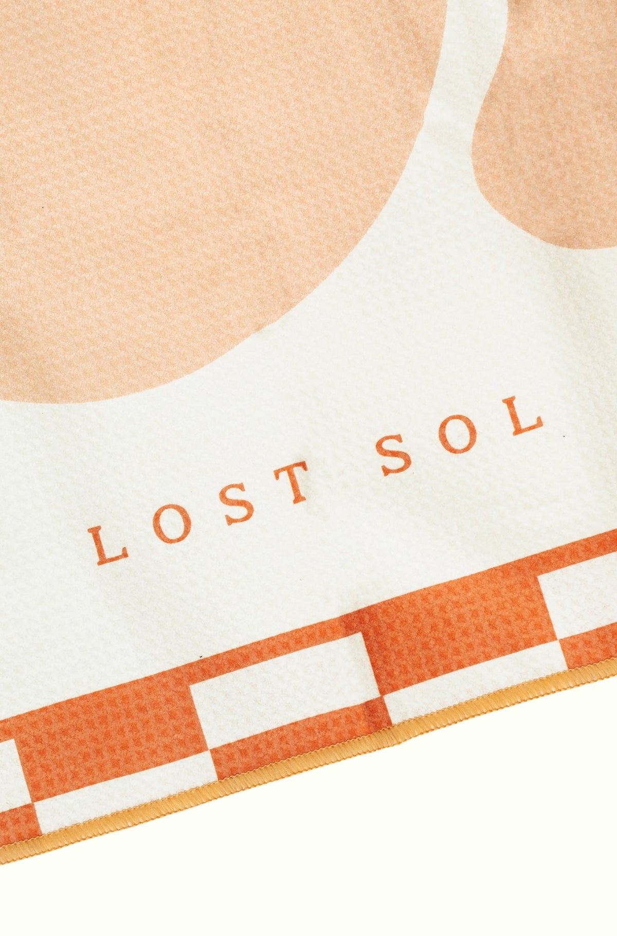 Mallorca Pastel quick-dry microfibre towel in soft peach, folded product shot on a yellow background