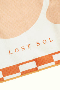 Mallorca Pastel quick-dry microfibre towel in soft peach, folded product shot on a yellow background