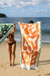 Lost Sol Mallorca Bold beach towel in burnt orange in use on holiday, lifestyle photo