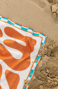 Mallorca Bold burnt orange beach towel shaking sand-free on the beach, Lost Sol lifestyle photo