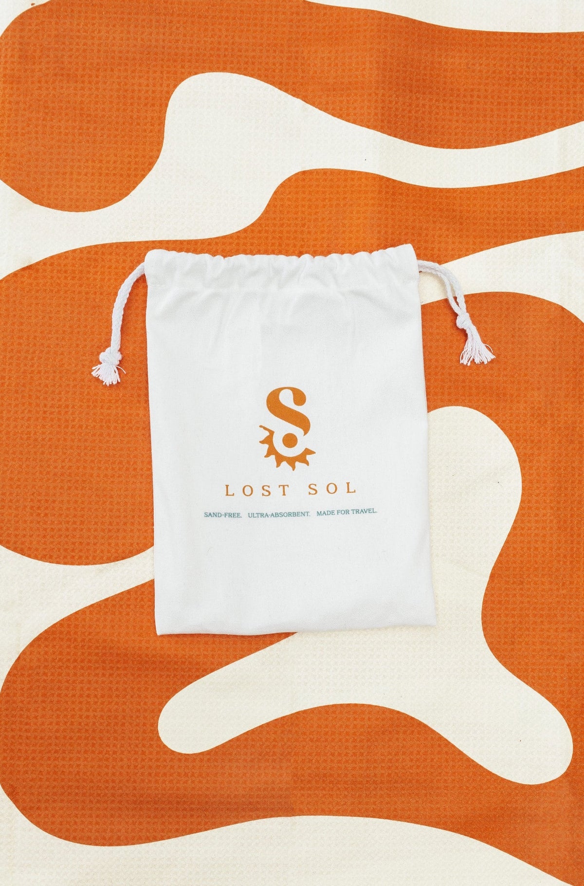 Compact packable Lost Sol Mallorca Bold microfibre towel in burnt orange, lifestyle photo