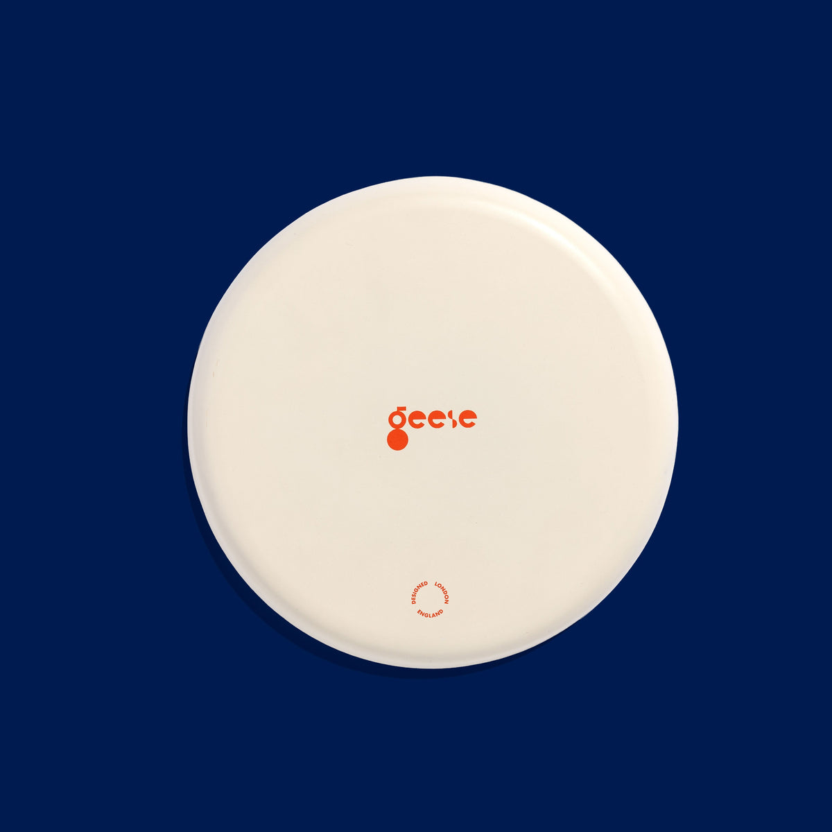Zero round enamel tray in cream with a large abstract dark blue splash by Geese