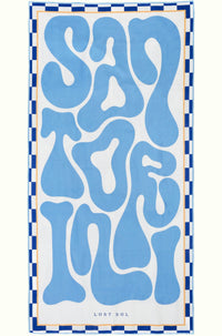 Santorini Pastel sand-free beach towel in soft sky blue by Lost Sol, laid flat on a yellow background