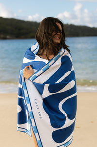 Lost Sol Santorini Bold beach towel in deep blue and white in use on holiday, lifestyle photo