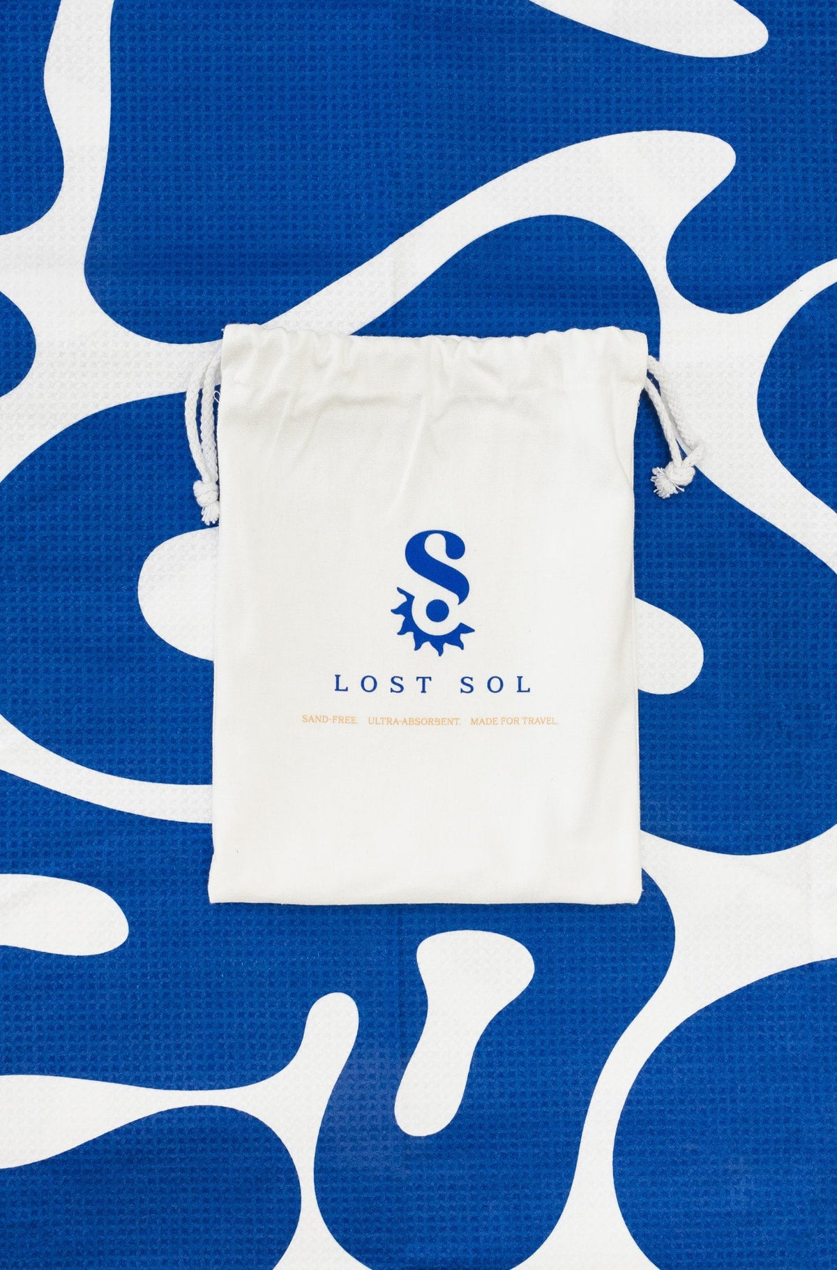 Compact packable Lost Sol Santorini Bold microfibre towel in deep blue and white, lifestyle photo