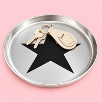 Zeus round enamelled aluminium tray with a black star motif by Geese