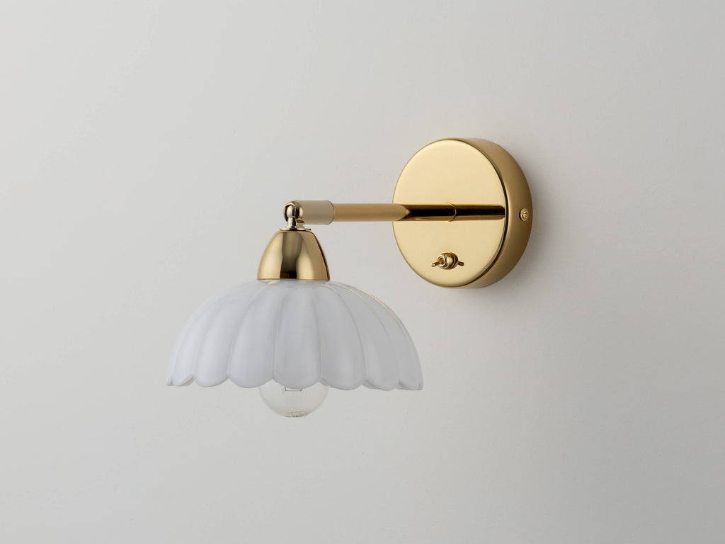 A flower-shaped milky-coloured glass mould shade is attached to a wall fixture. Light is off.