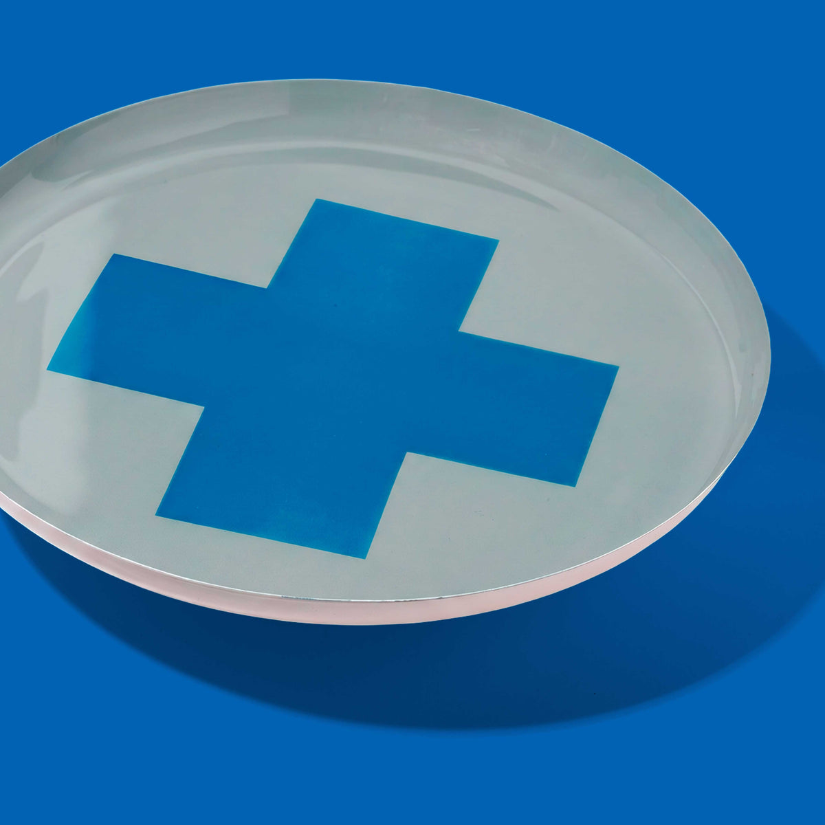 Zeppelin round enamel tray in grey with a contrast blue cross design by Geese