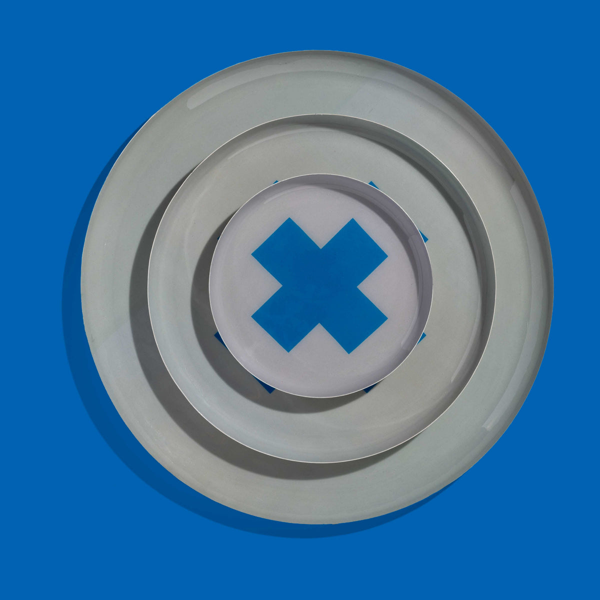 Zeppelin round enamel tray in grey with a contrast blue cross design by Geese