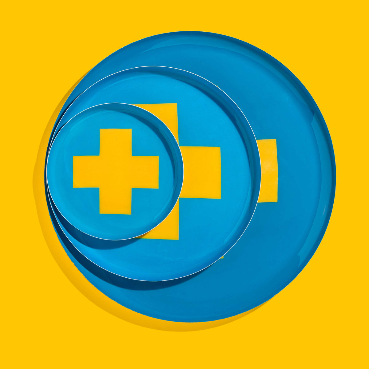 Zeppelin round enamel tray in blue with a vibrant yellow cross design by Geese