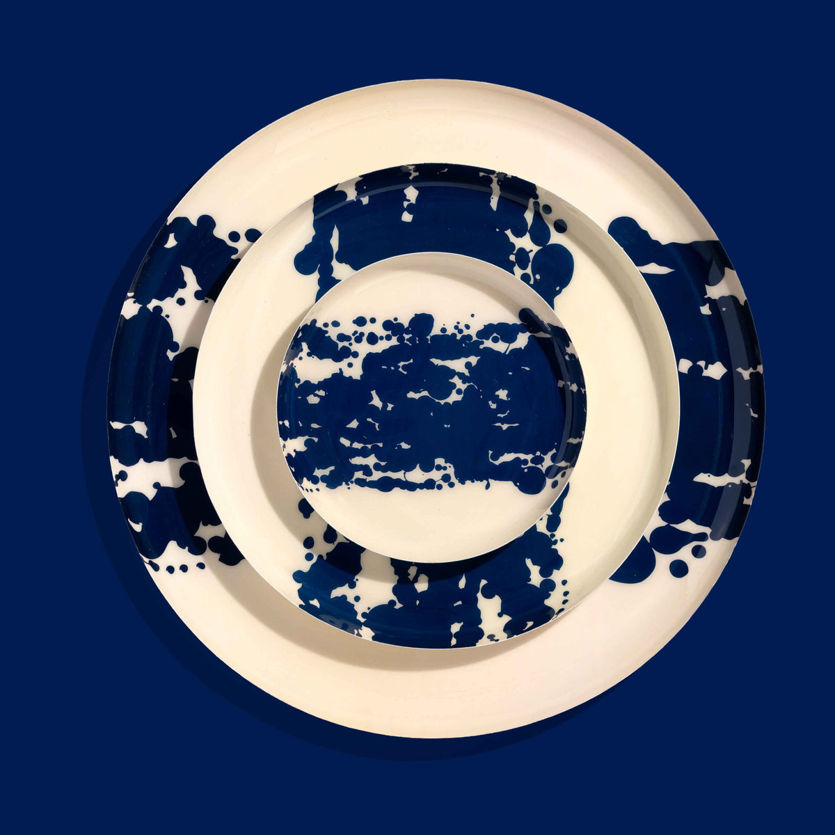 Zero round enamel tray in cream with a large abstract dark blue splash by Geese