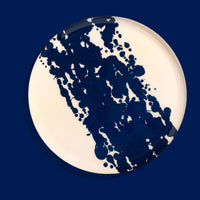 Zero round enamel tray in cream with a large abstract dark blue splash by Geese