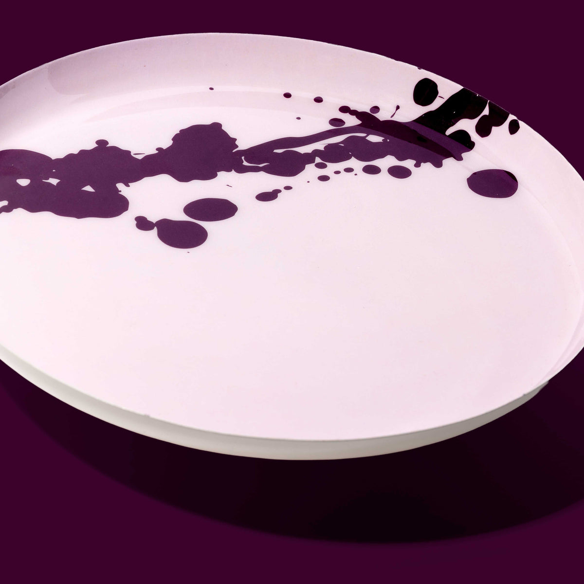 Zilla round enamel tray in pink with an abstract purple splash design by Geese