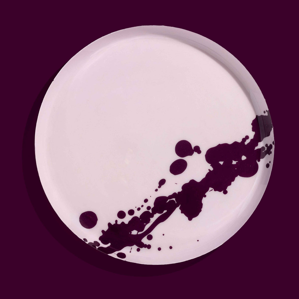 Zilla round enamel tray in pink with an abstract purple splash design by Geese