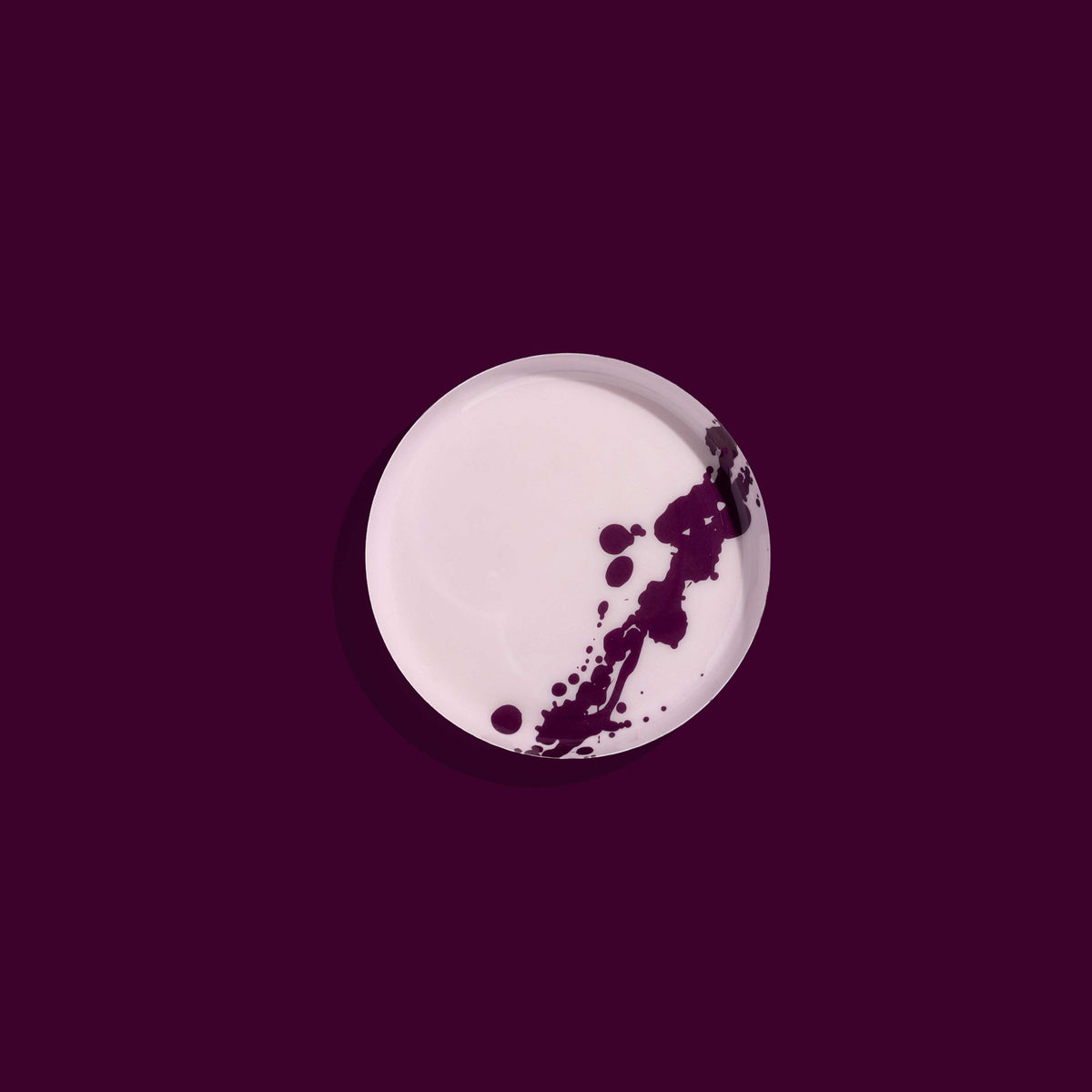 Zilla round enamel tray in pink with an abstract purple splash design by Geese