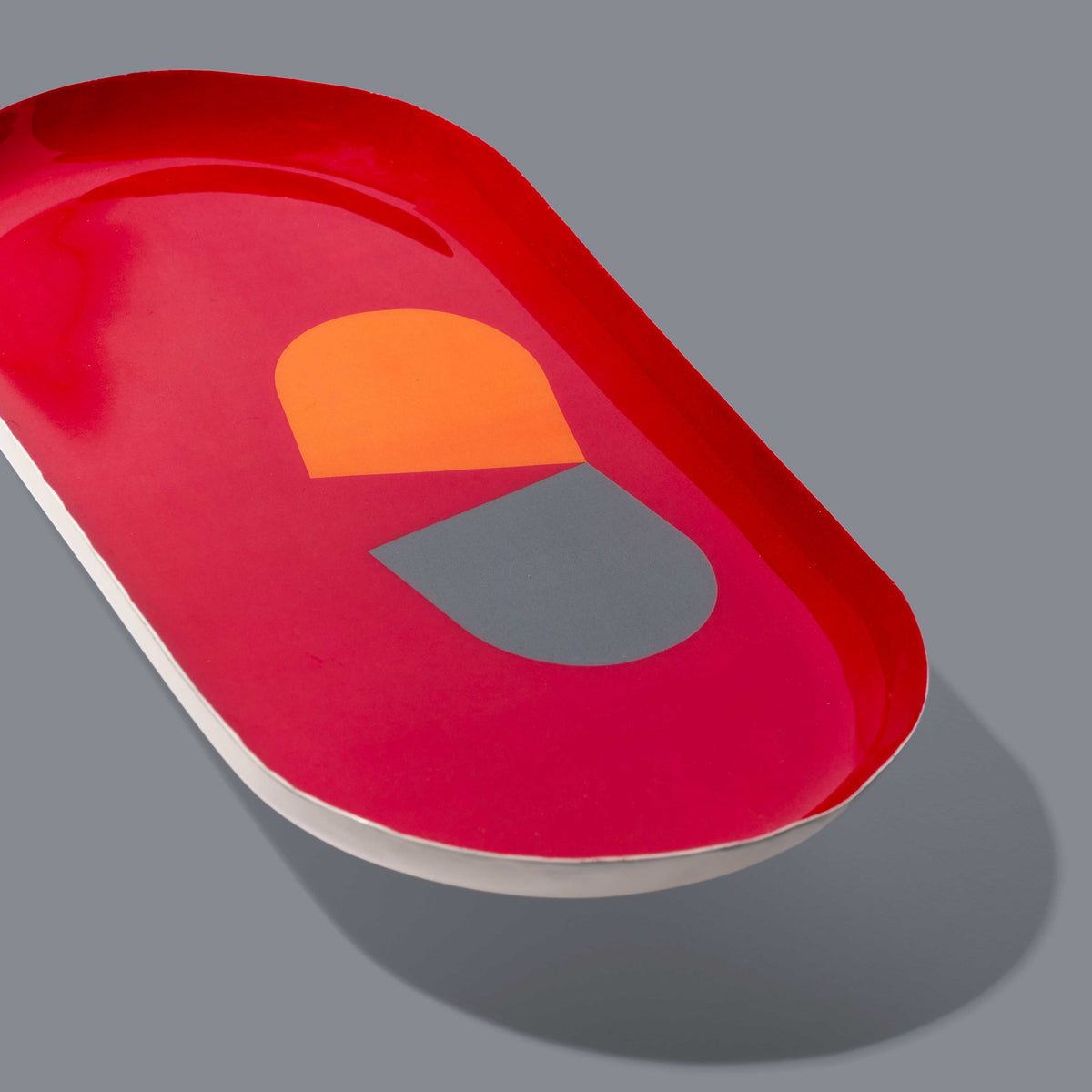 Zombie capsule enamel tray in deep red with an orange and grey split pill design by Geese