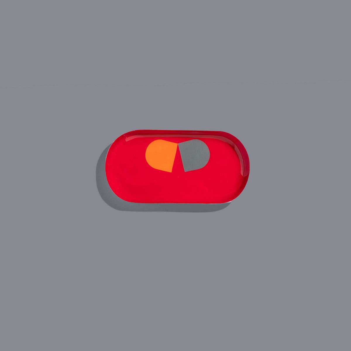 Zombie capsule enamel tray in deep red with an orange and grey split pill design by Geese