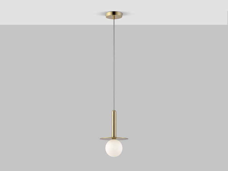 A brass pendant ceiling light with a brass oval body and a horizontal brass metal plate that holds a white opal glass shade. Light is on.