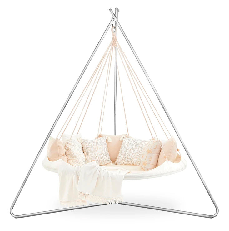 Bohemian-style hanging bed with a beige canopy, decorative pillows, and a throw blanket, designed for outdoor or indoor lounging.